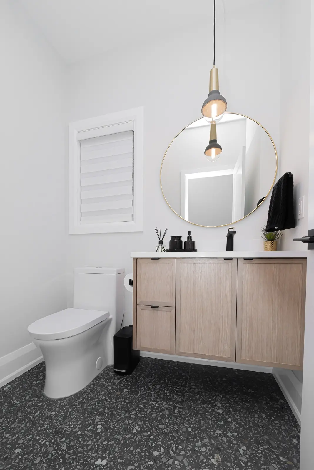 Interior of a Thornhill detached house renovation, with pale wood floors, black furnishings, and a walnut vanity in the primary bathroom.