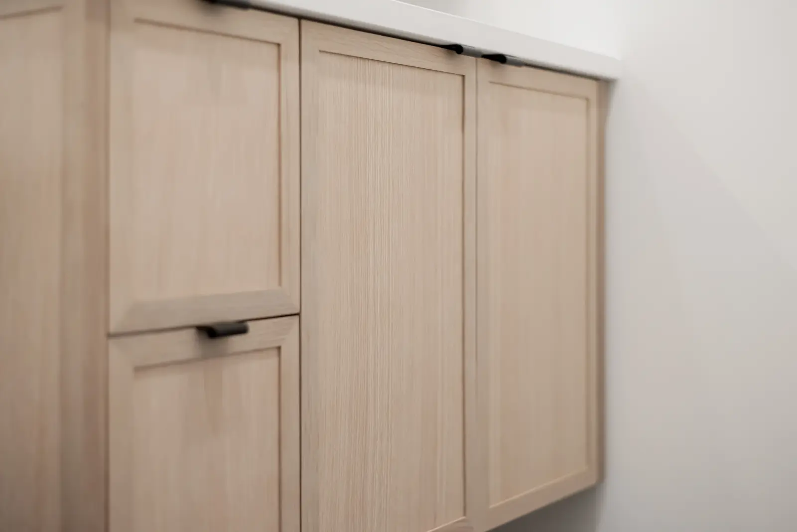 Interior of a Thornhill detached house renovation, with pale wood floors, black furnishings, and a walnut vanity in the primary bathroom.