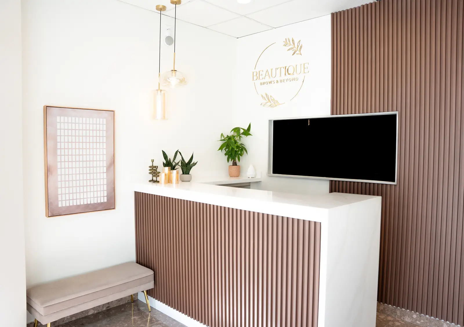 Reception of a Thornhill salon, with a fluted wood desk, a white counter, and a gold Beautique logo.
