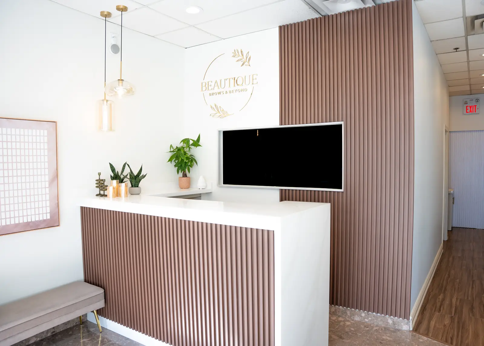 Reception of a Thornhill salon, with a fluted wood desk, a white counter, and a gold Beautique logo.