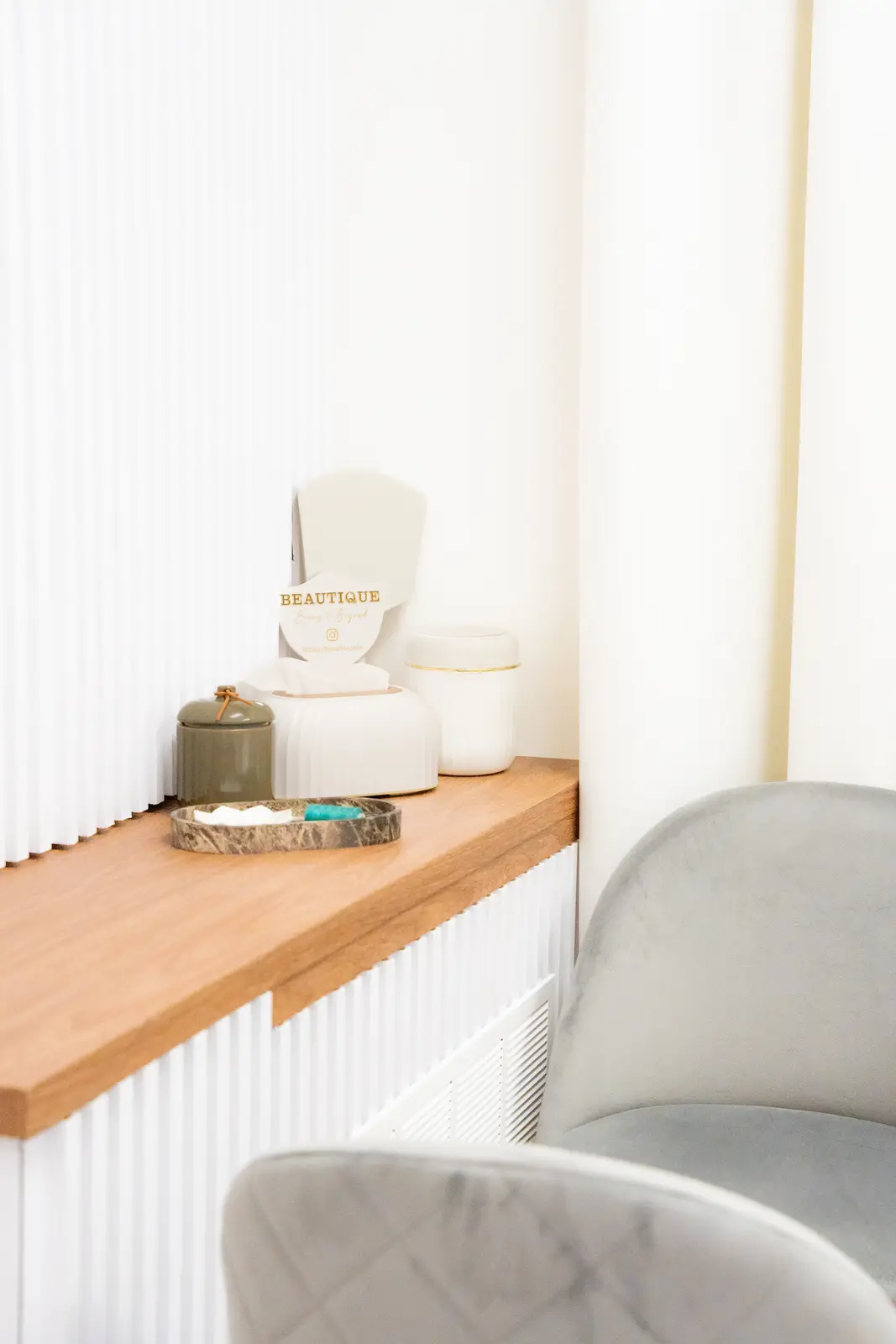 Reception of a Thornhill salon, with a fluted wood desk, a white counter, and a gold Beautique logo.