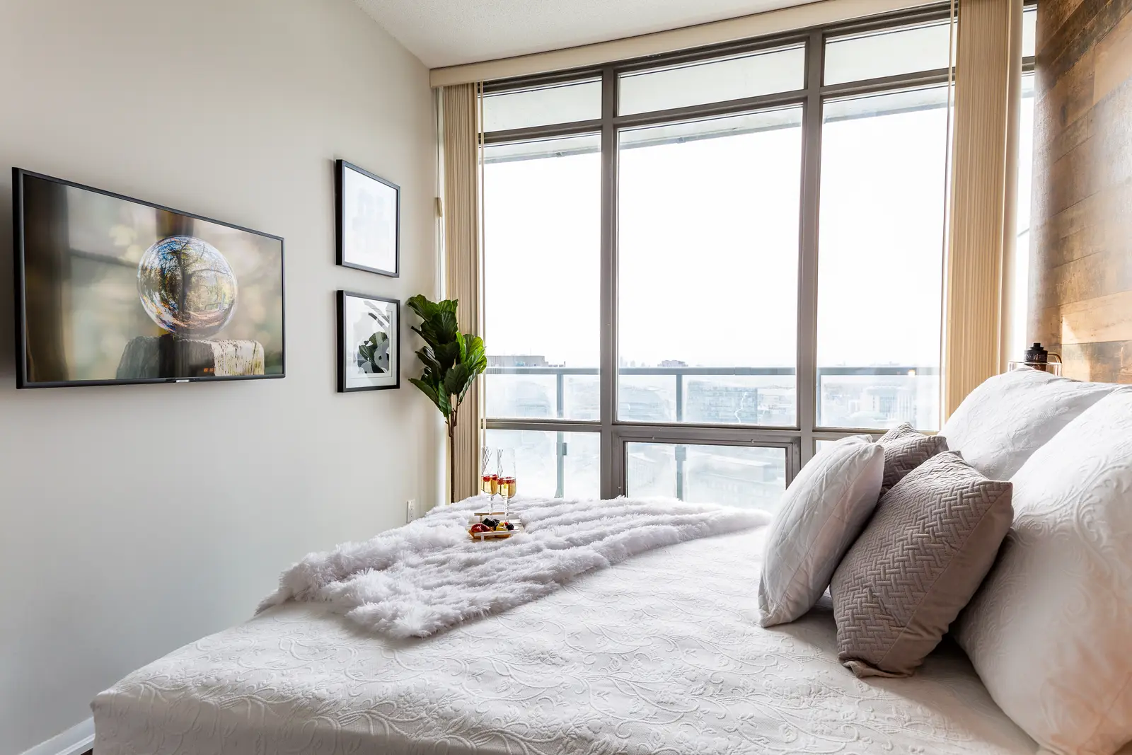 Interior of a Bay Street condo in Toronto, with a grey sofa, a dark kitchen, and city windows.