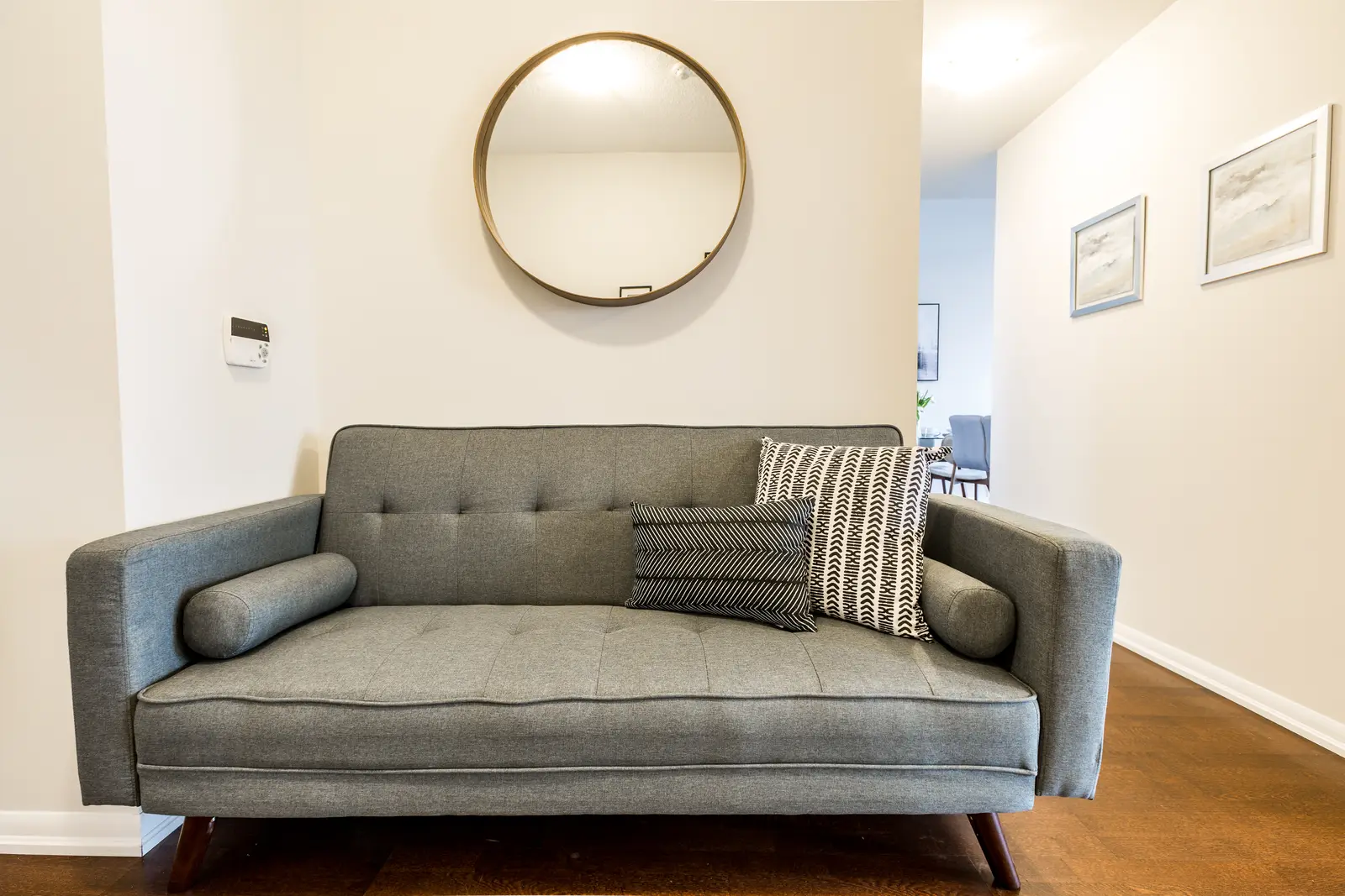 Interior of a Bay Street condo in Toronto, with a grey sofa, a dark kitchen, and city windows.