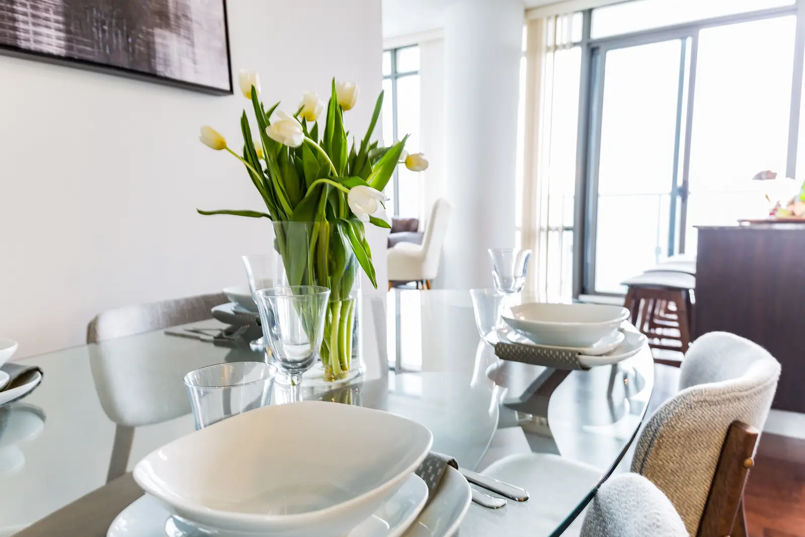 Interior of a Bay Street condo in Toronto, with a grey sofa, a dark kitchen, and city windows.