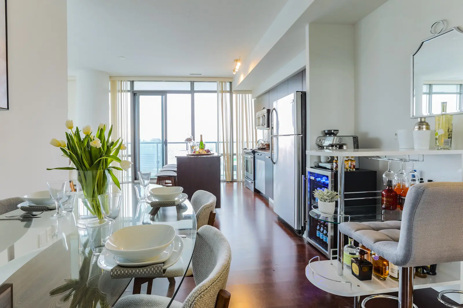 Interior of a Bay Street condo in Toronto, with a grey sofa, a dark kitchen, and city windows.