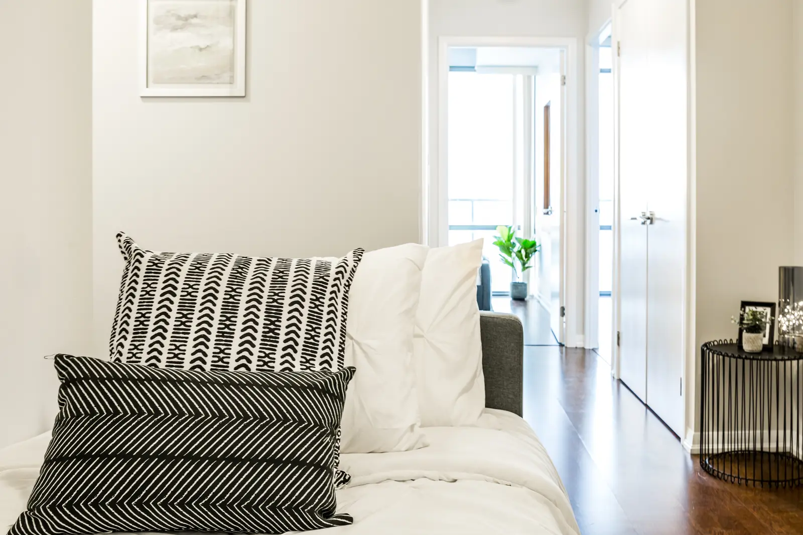 Interior of a Bay Street condo in Toronto, with a grey sofa, a dark kitchen, and city windows.