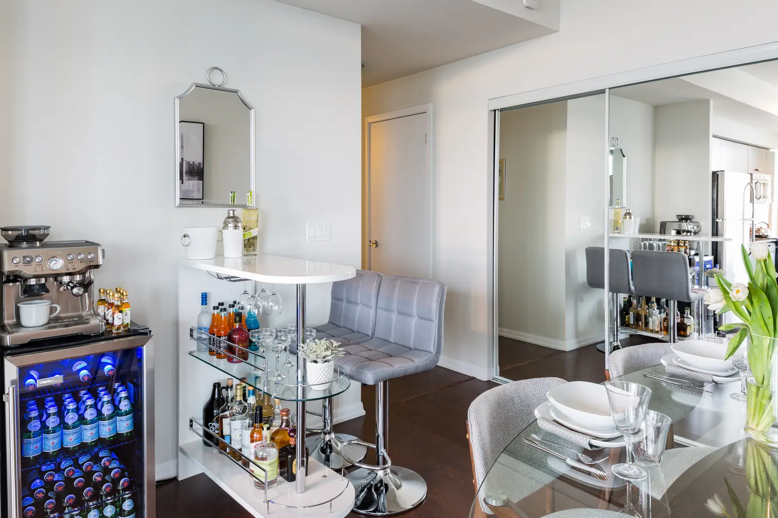 Interior of a Bay Street condo in Toronto, with a grey sofa, a dark kitchen, and city windows.