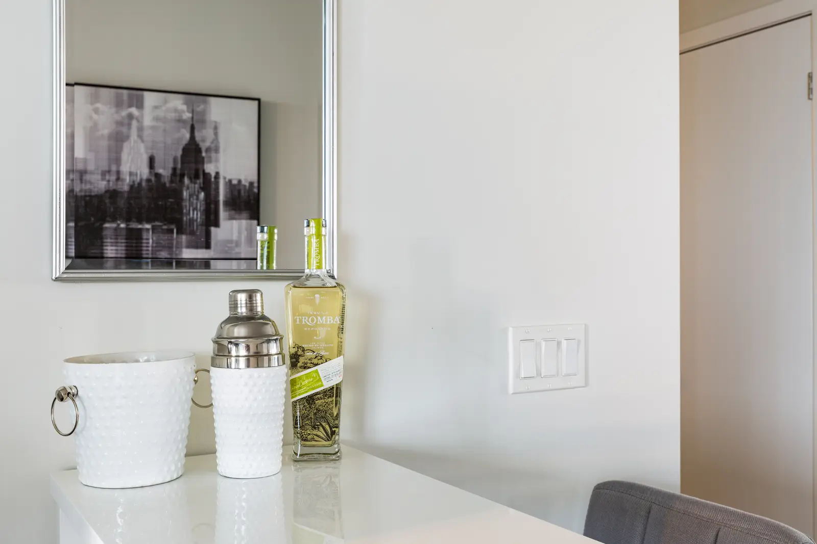 Interior of a Bay Street condo in Toronto, with a grey sofa, a dark kitchen, and city windows.