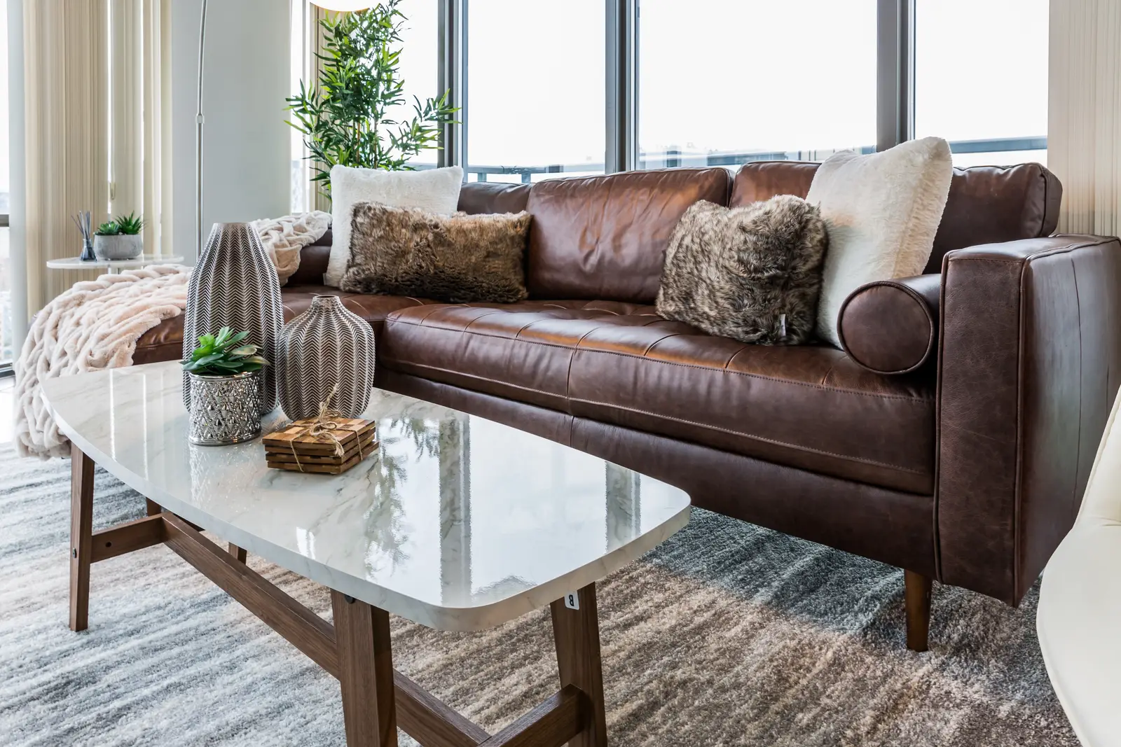 Interior of a Bay Street condo in Toronto, with a grey sofa, a dark kitchen, and city windows.
