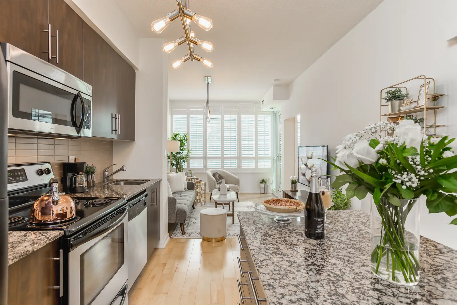 Interior of a downtown Toronto condo, with a wood kitchen, a grey sofa, and a balcony.