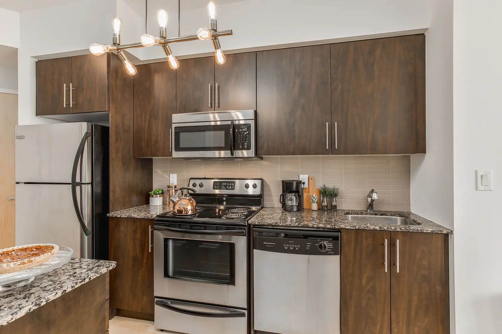 Interior of a downtown Toronto condo, with a wood kitchen, a grey sofa, and a balcony.