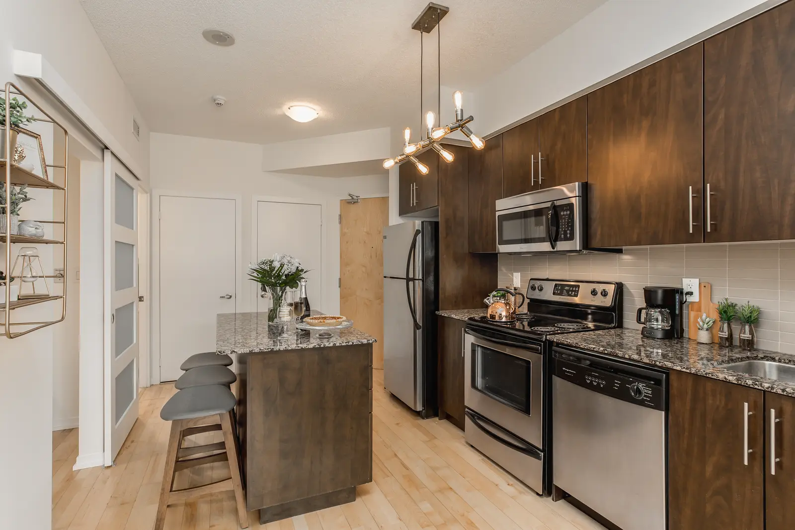 Interior of a downtown Toronto condo, with a wood kitchen, a grey sofa, and a balcony.