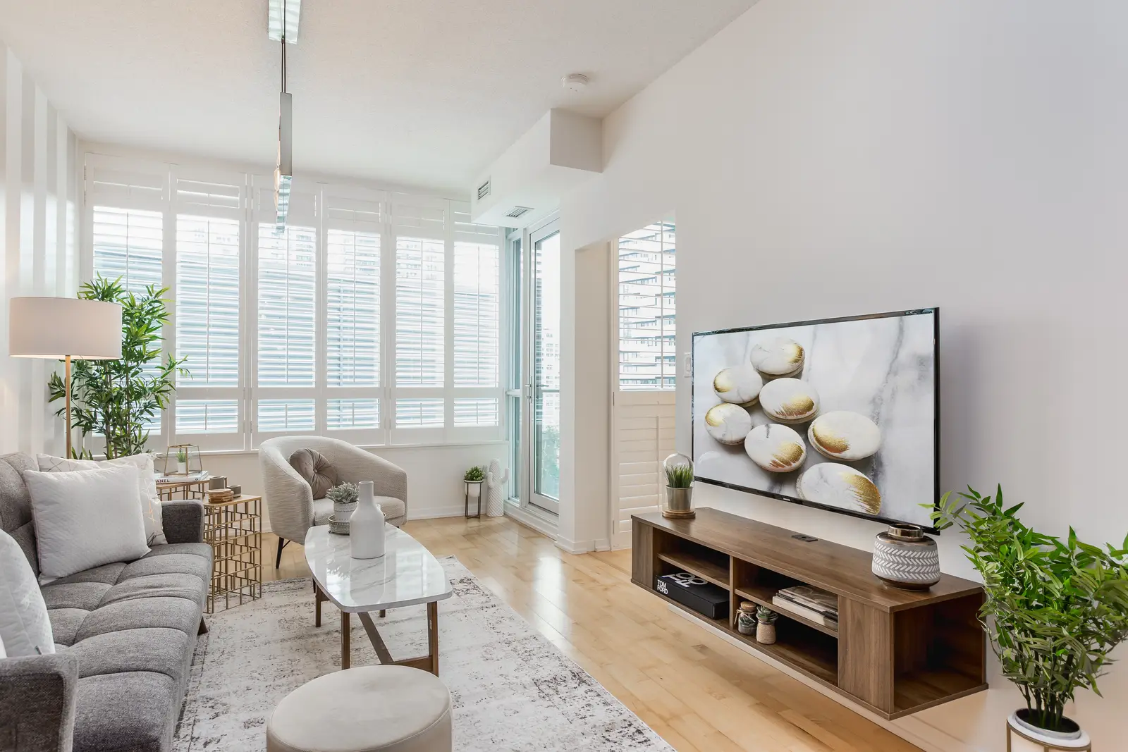 Interior of a downtown Toronto condo, with a wood kitchen, a grey sofa, and a balcony.