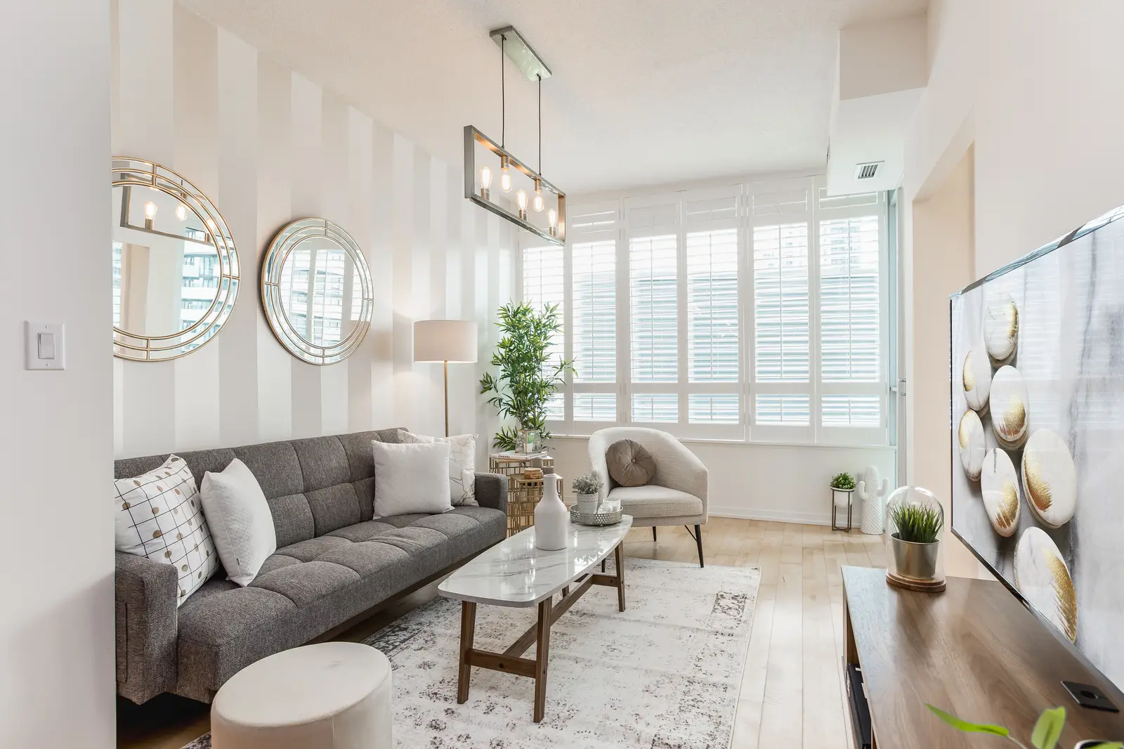 Interior of a downtown Toronto condo, with a wood kitchen, a grey sofa, and a balcony.
