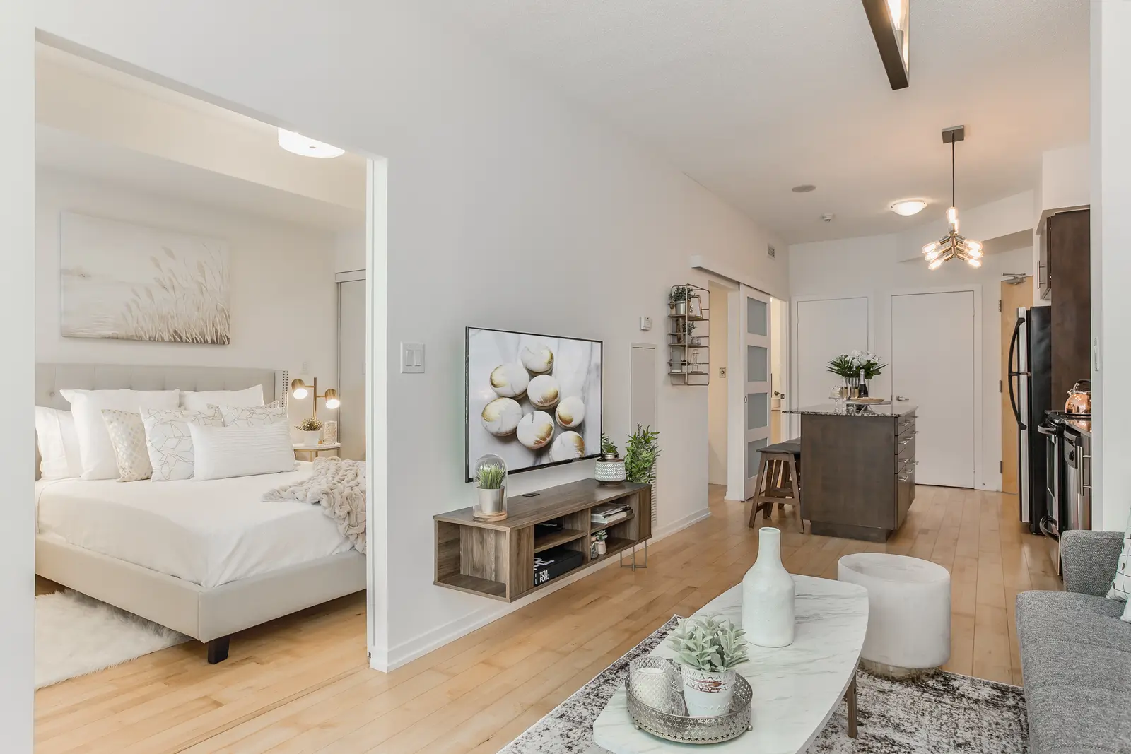 Interior of a downtown Toronto condo, with a wood kitchen, a grey sofa, and a balcony.