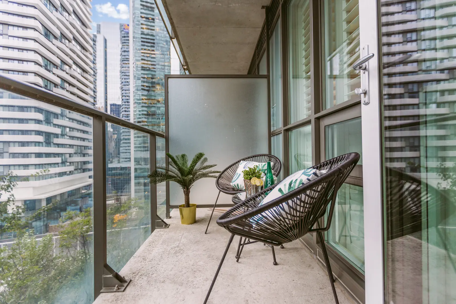 Interior of a downtown Toronto condo, with a wood kitchen, a grey sofa, and a balcony.