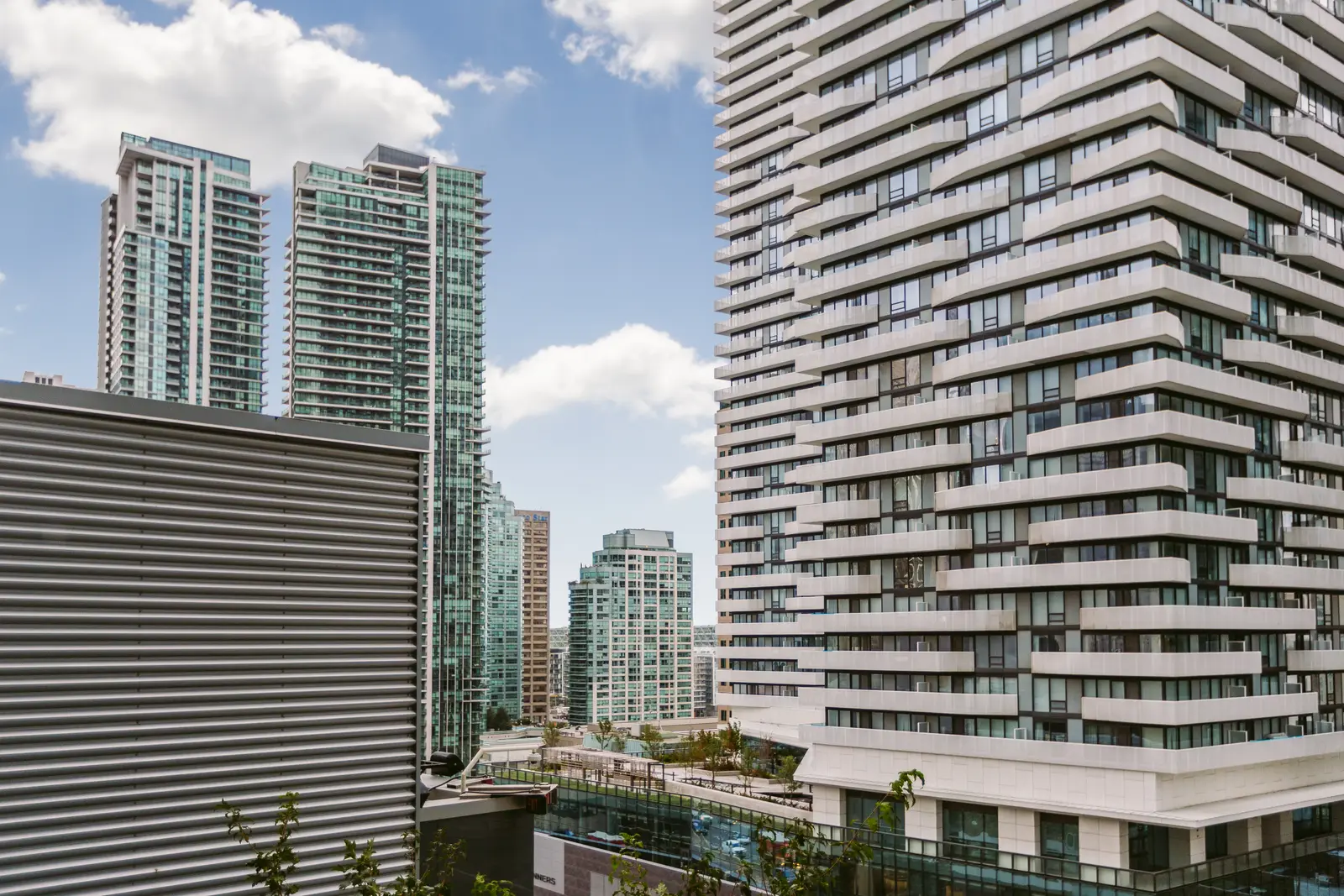 Interior of a downtown Toronto condo, with a wood kitchen, a grey sofa, and a balcony.