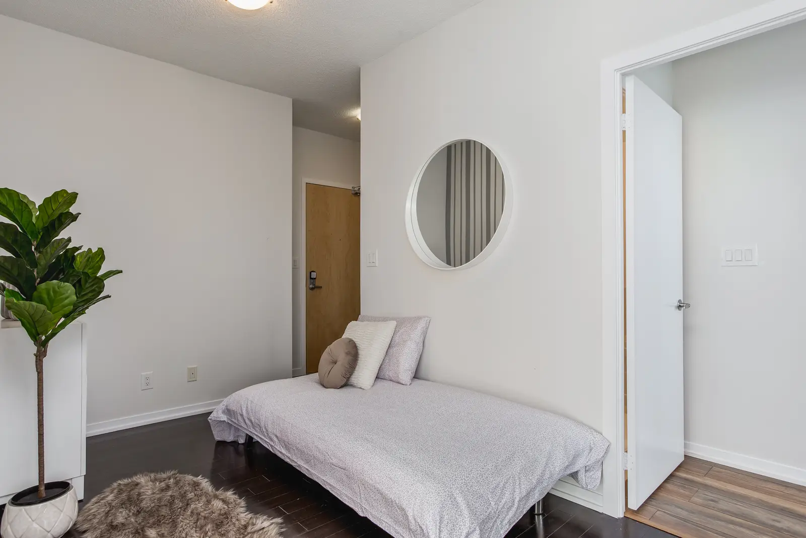 Interior of a waterfront condo in Toronto, with a grey sofa, a light kitchen, and a view of the lake.