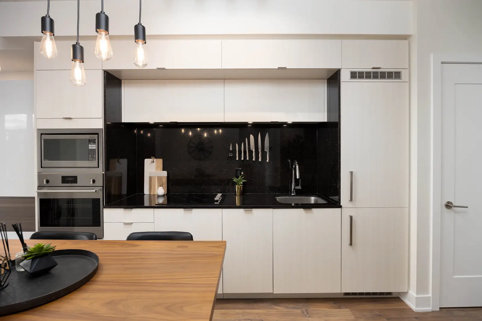 Interior of a Queen West condo in Toronto, with a grey sectional, a white kitchen, and black counters.