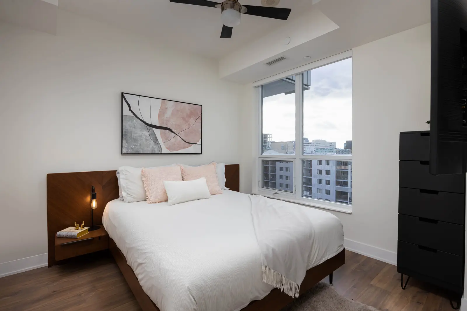 Interior of a Queen West condo in Toronto, with a grey sectional, a white kitchen, and black counters.
