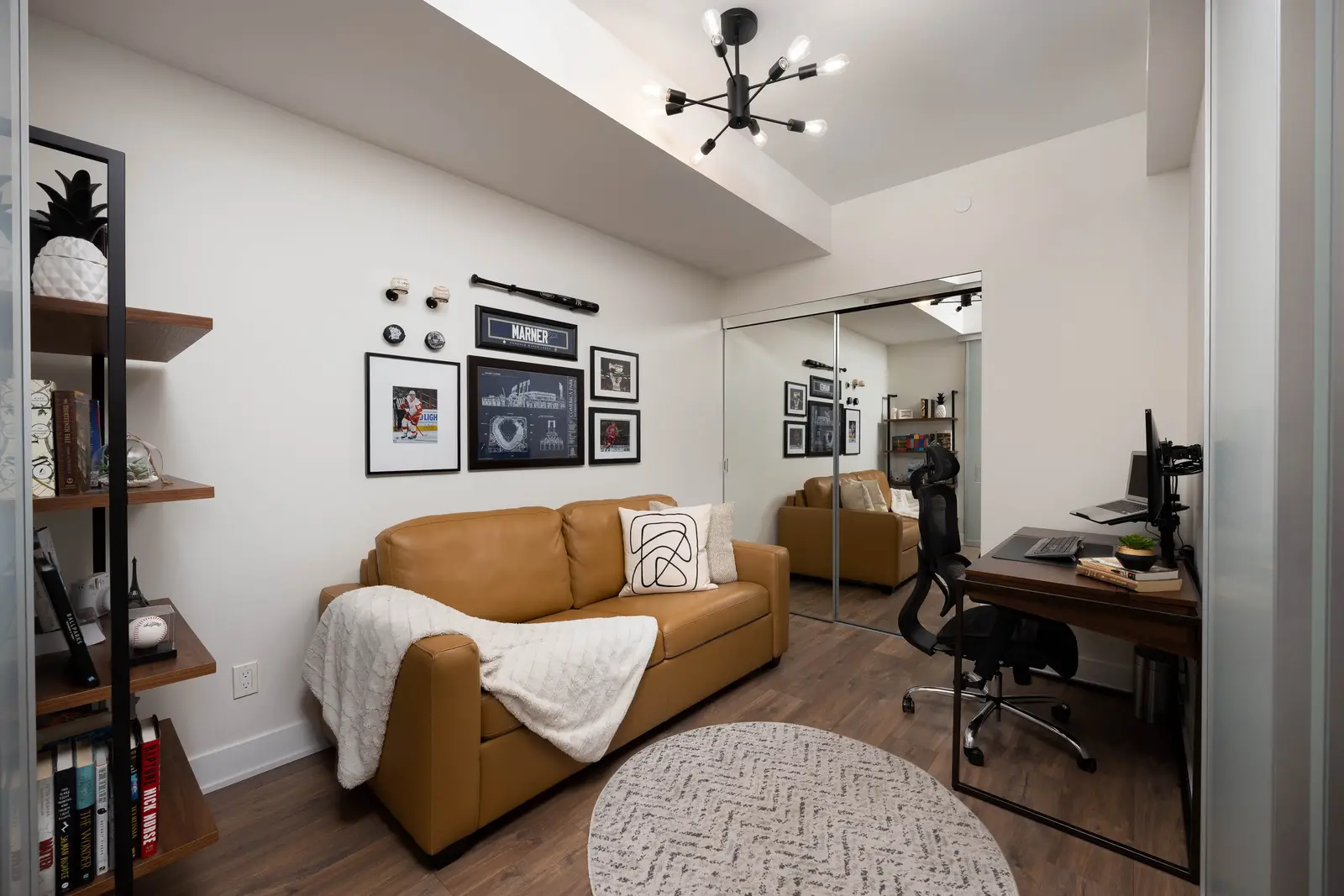 Interior of a Queen West condo in Toronto, with a grey sectional, a white kitchen, and black counters.