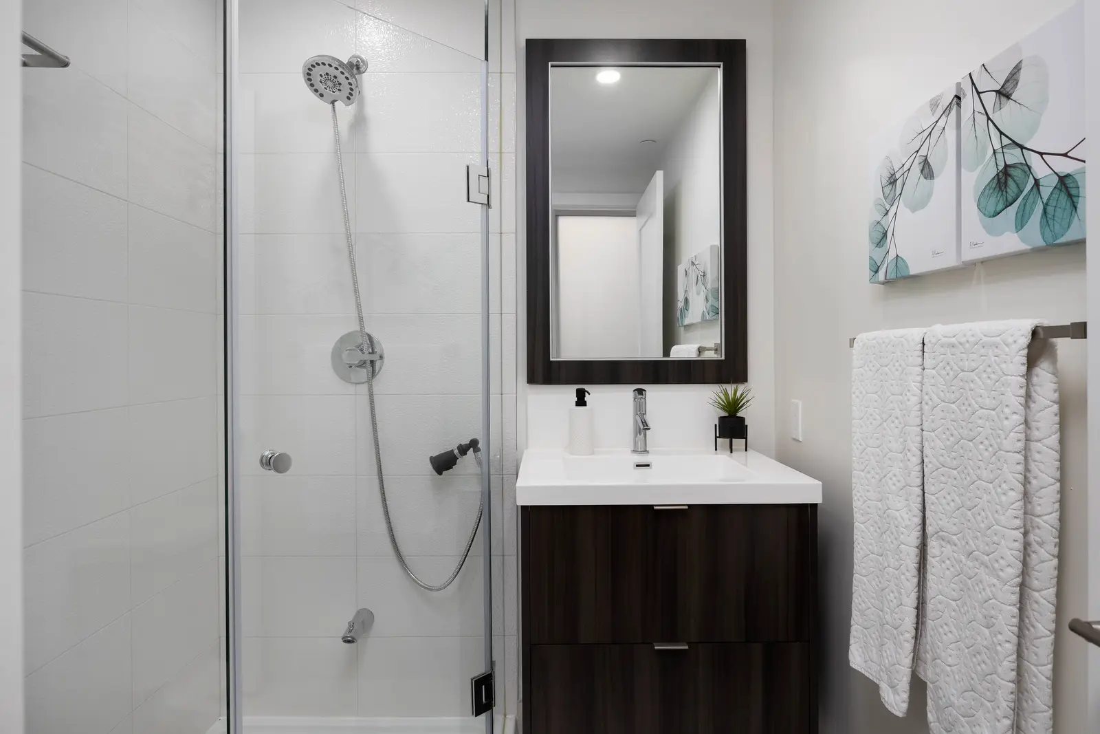 Interior of a Queen West condo in Toronto, with a grey sectional, a white kitchen, and black counters.