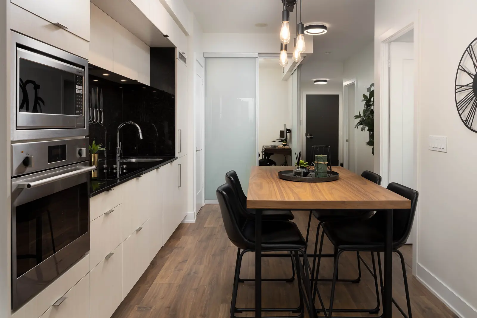 Interior of a Queen West condo in Toronto, with a grey sectional, a white kitchen, and black counters.