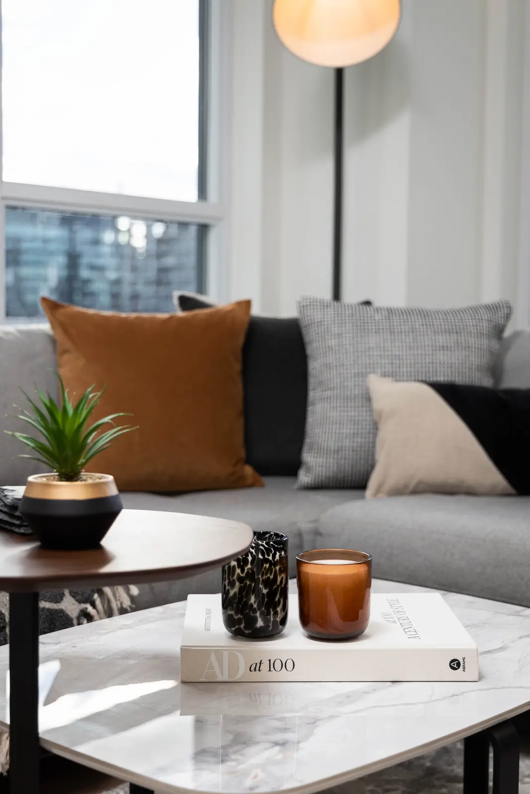 Interior of a Queen West condo in Toronto, with a grey sectional, a white kitchen, and black counters.