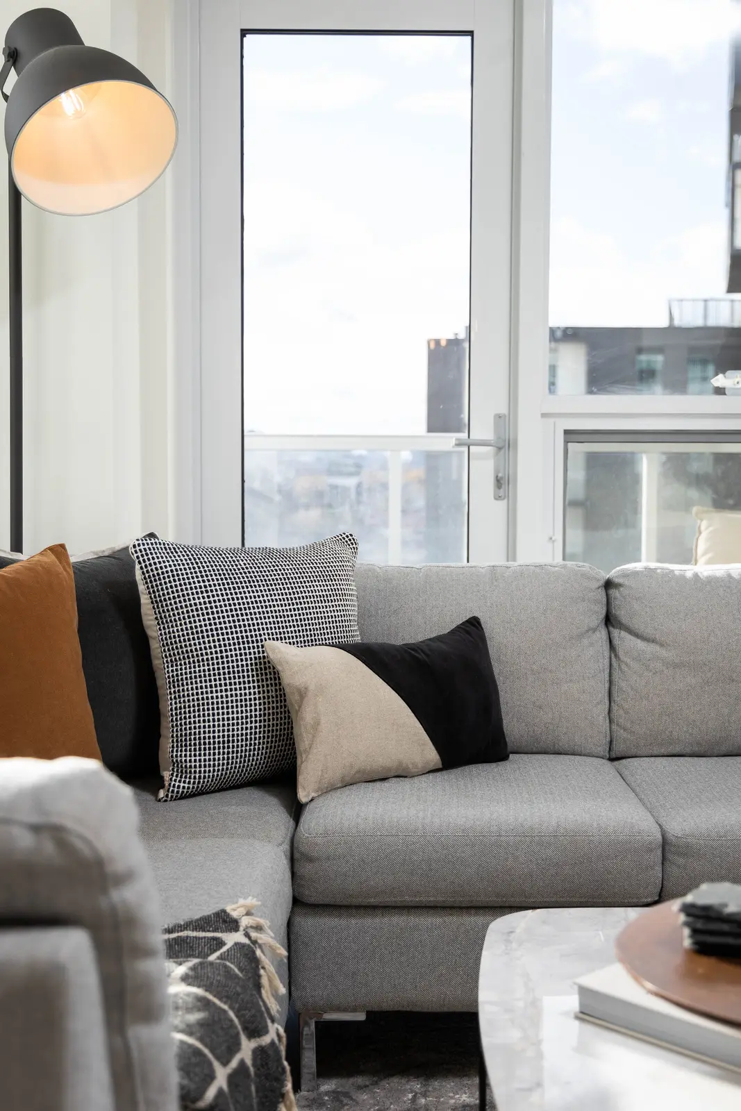 Interior of a Queen West condo in Toronto, with a grey sectional, a white kitchen, and black counters.