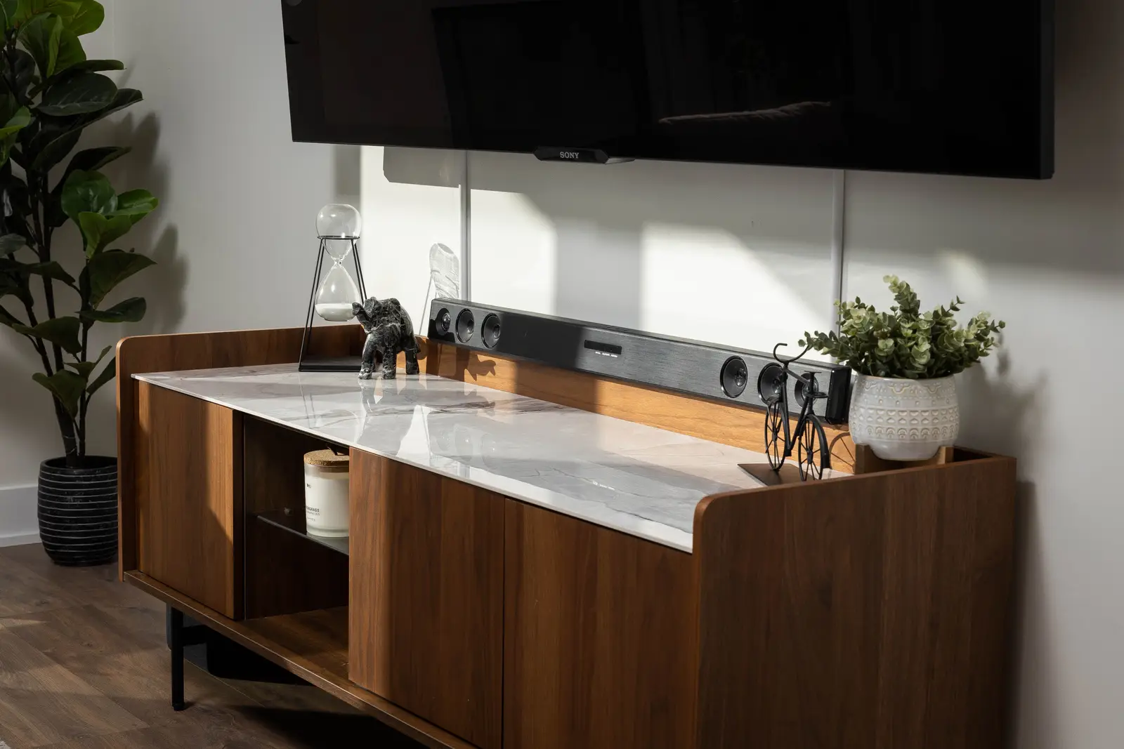 Interior of a Queen West condo in Toronto, with a grey sectional, a white kitchen, and black counters.