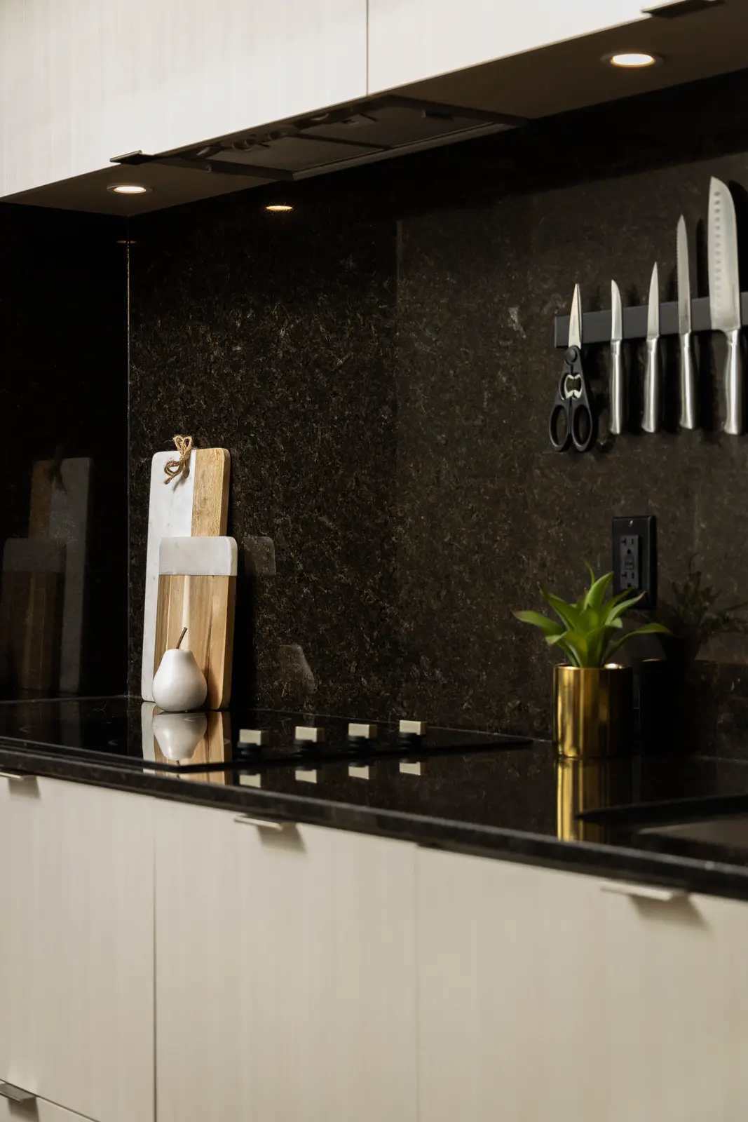 Interior of a Queen West condo in Toronto, with a grey sectional, a white kitchen, and black counters.