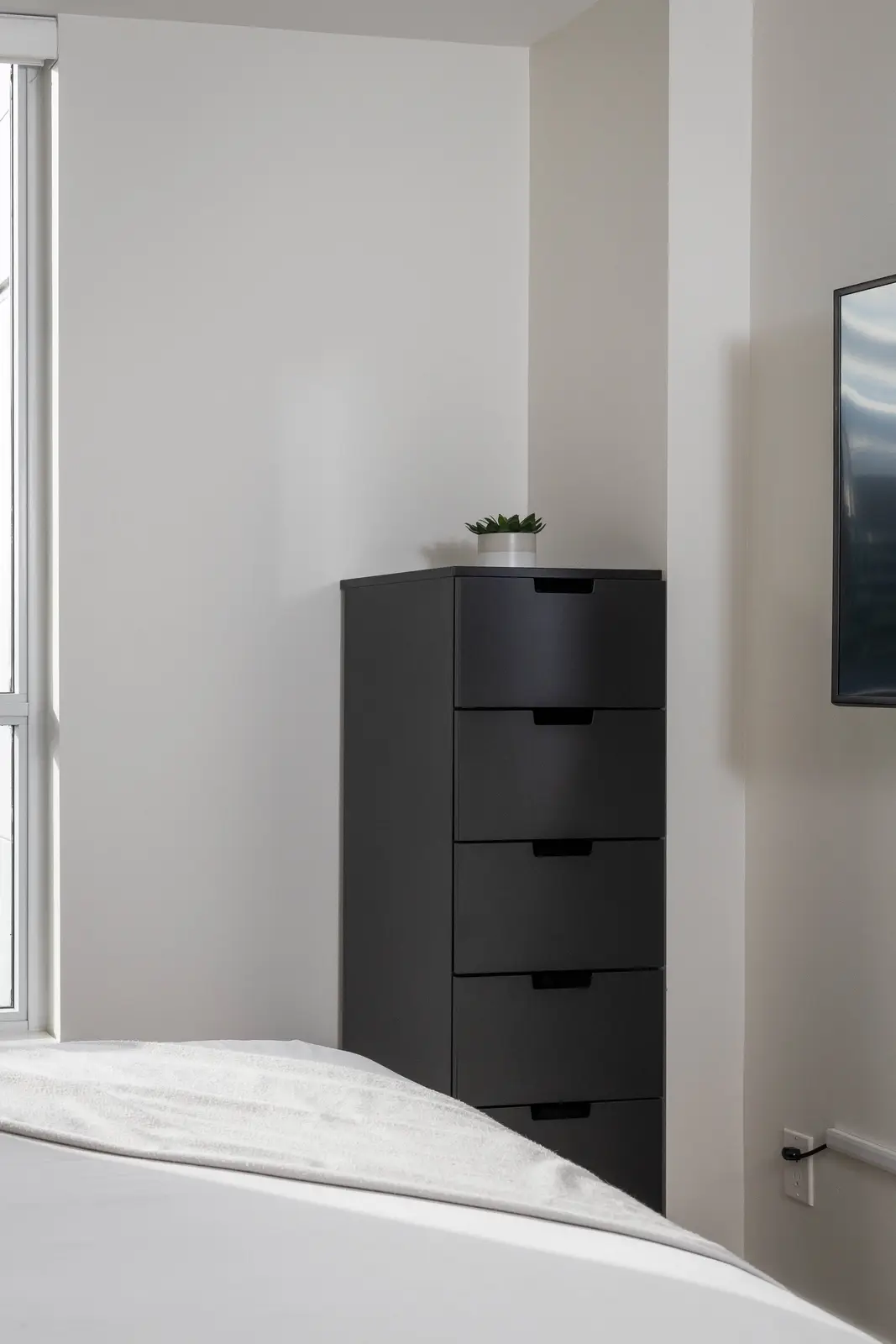 Interior of a Queen West condo in Toronto, with a grey sectional, a white kitchen, and black counters.