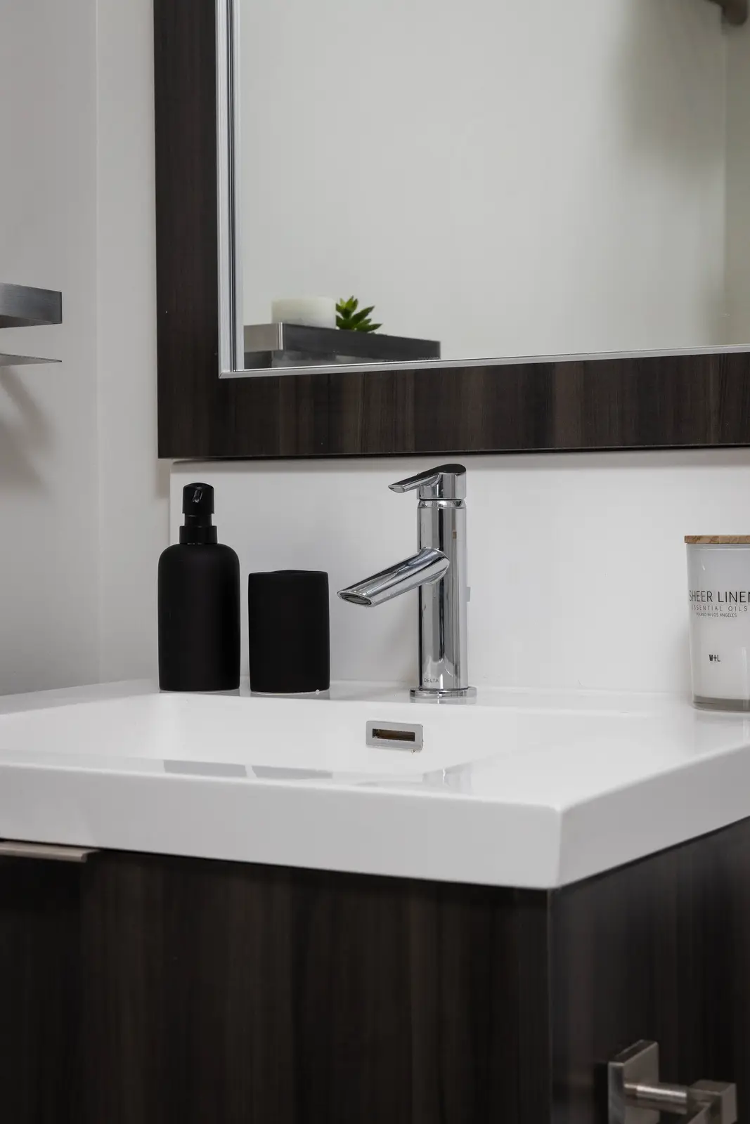 Interior of a Queen West condo in Toronto, with a grey sectional, a white kitchen, and black counters.