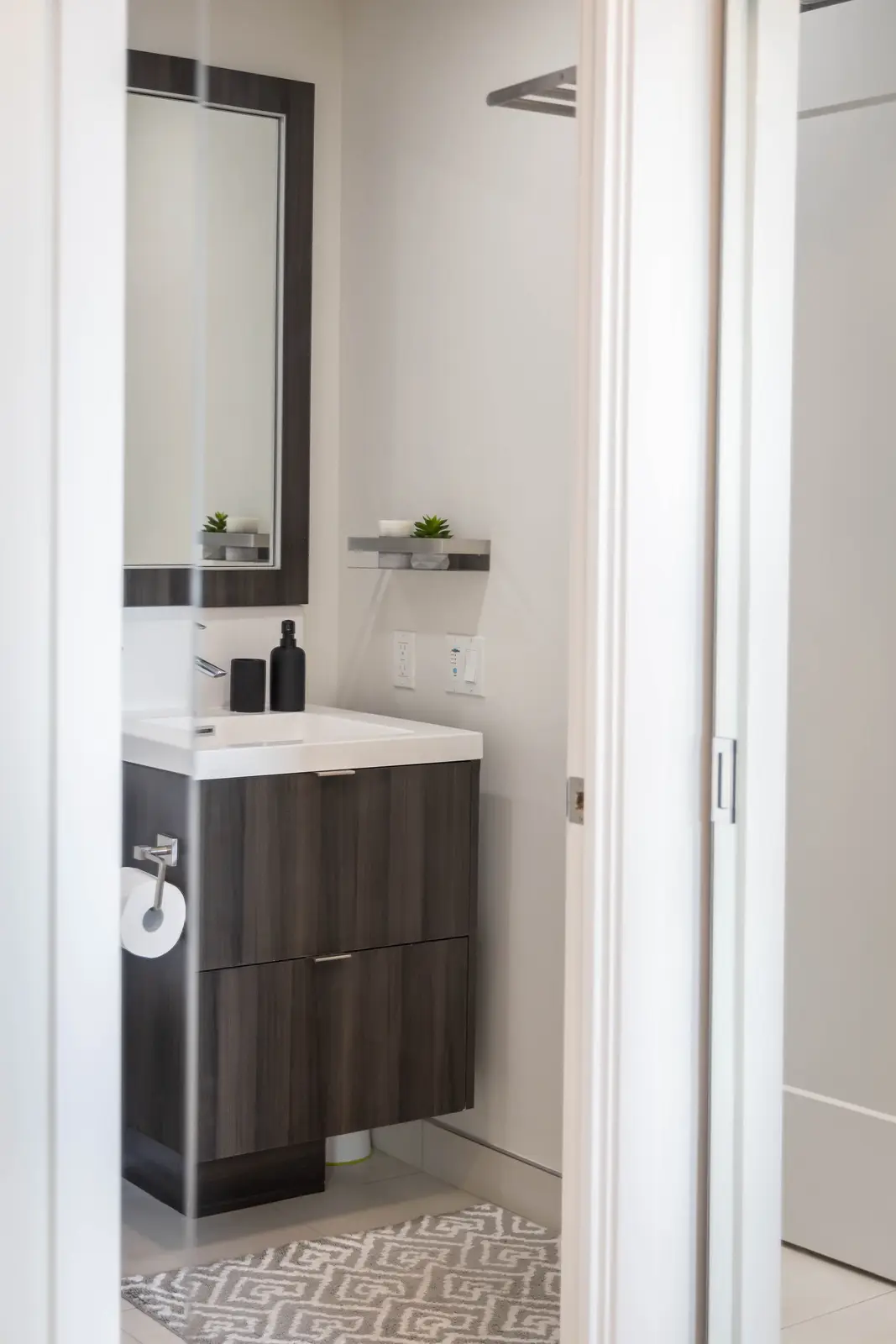 Interior of a Queen West condo in Toronto, with a grey sectional, a white kitchen, and black counters.