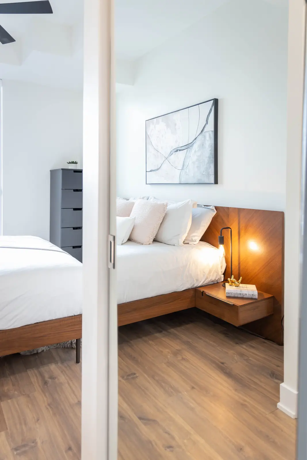 Interior of a Queen West condo in Toronto, with a grey sectional, a white kitchen, and black counters.