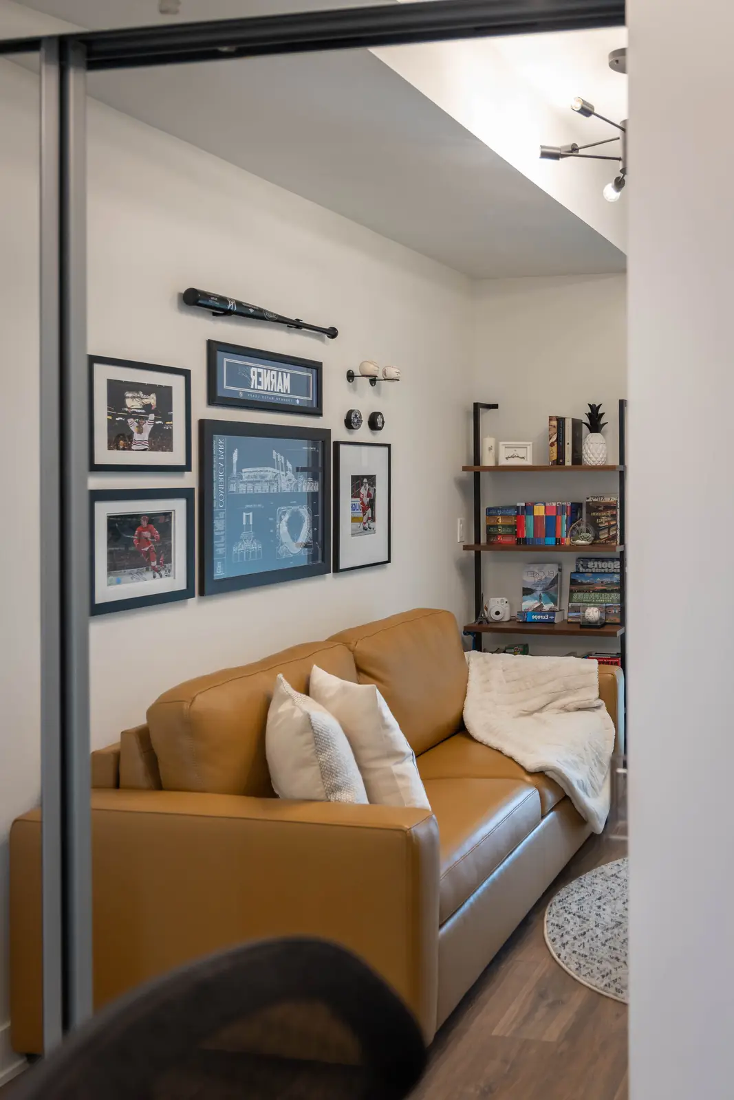 Interior of a Queen West condo in Toronto, with a grey sectional, a white kitchen, and black counters.