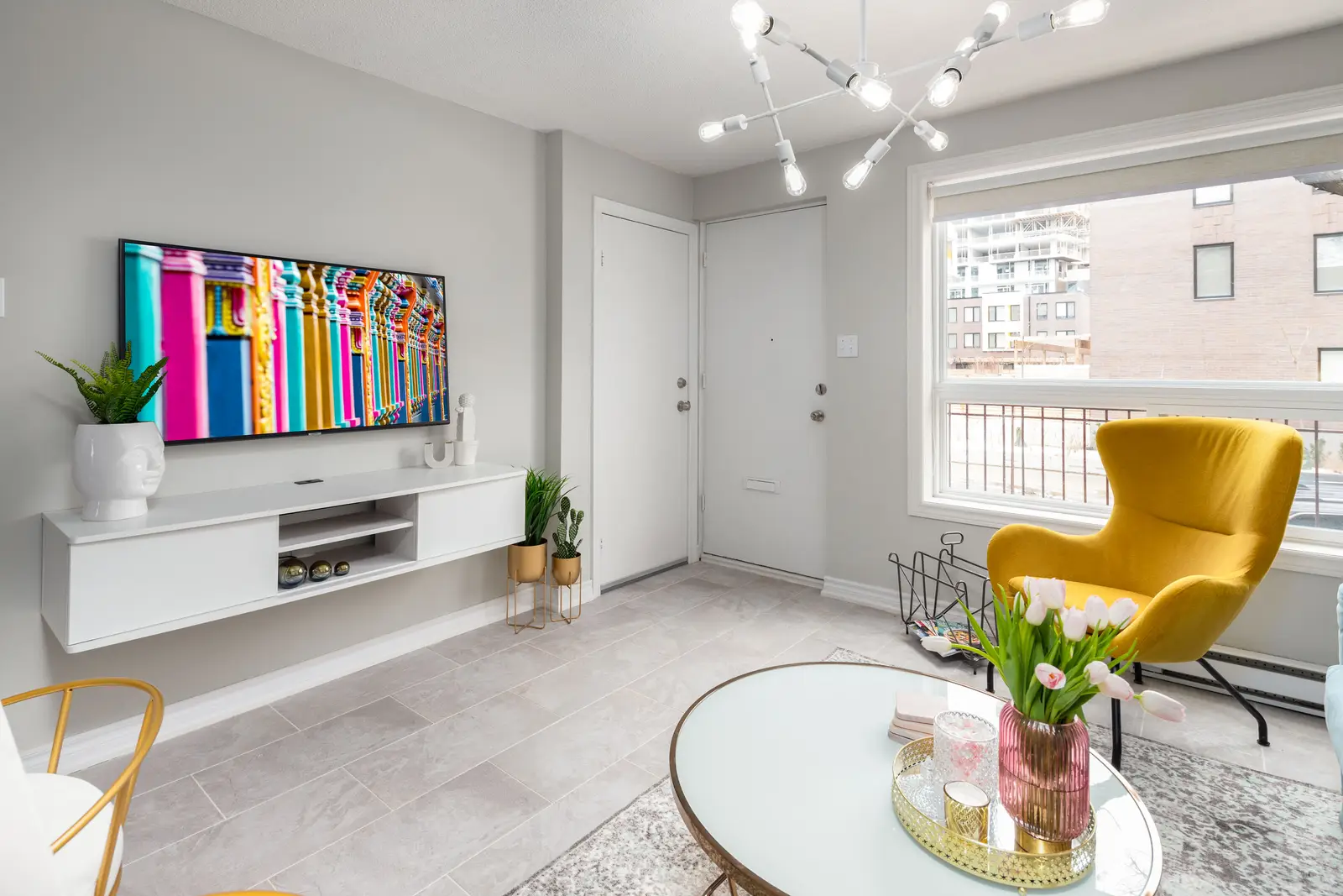 Interior of an apartment on Clinton Street in Toronto, with a blue sofa, a yellow chair, and a white kitchen.