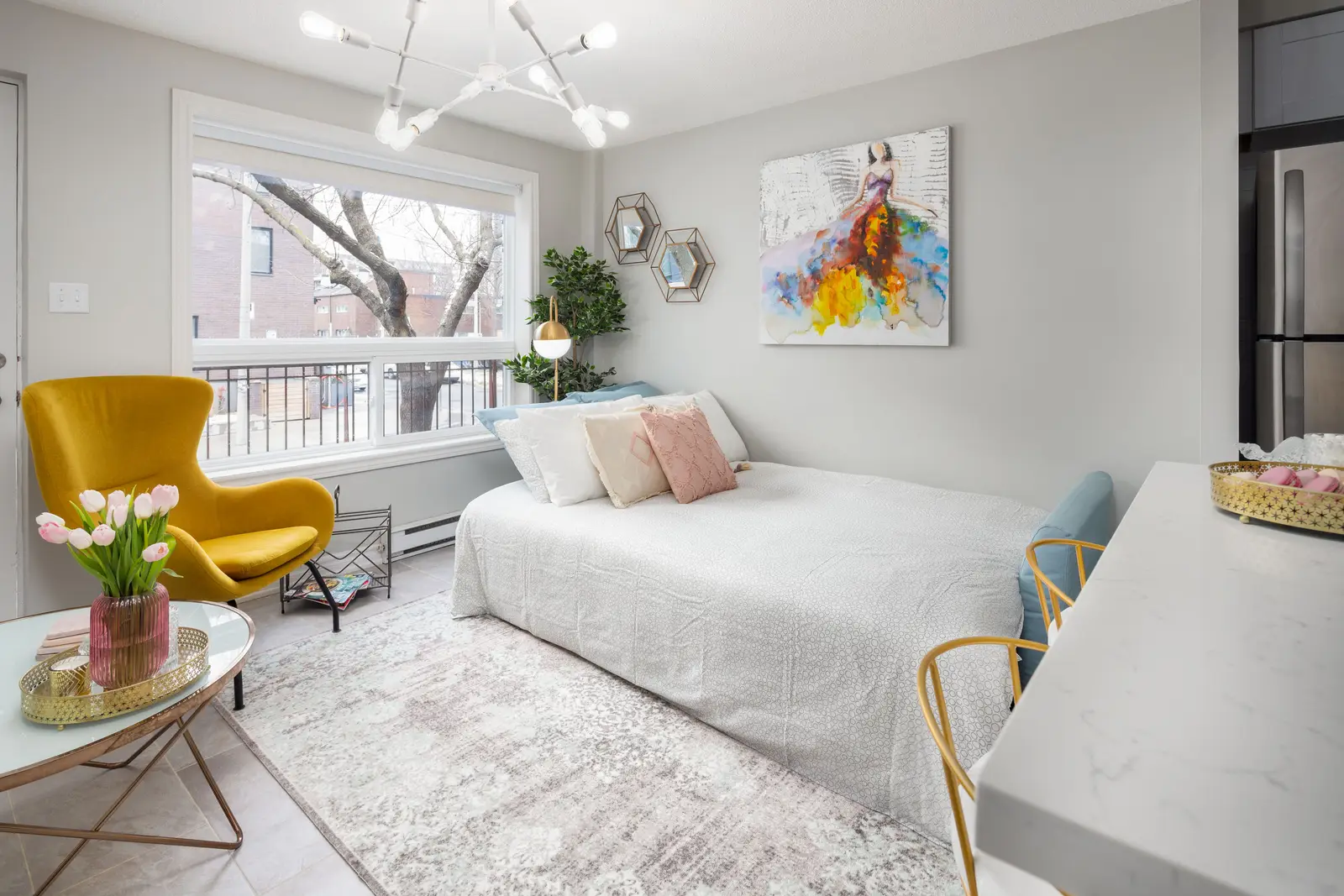 Interior of an apartment on Clinton Street in Toronto, with a blue sofa, a yellow chair, and a white kitchen.