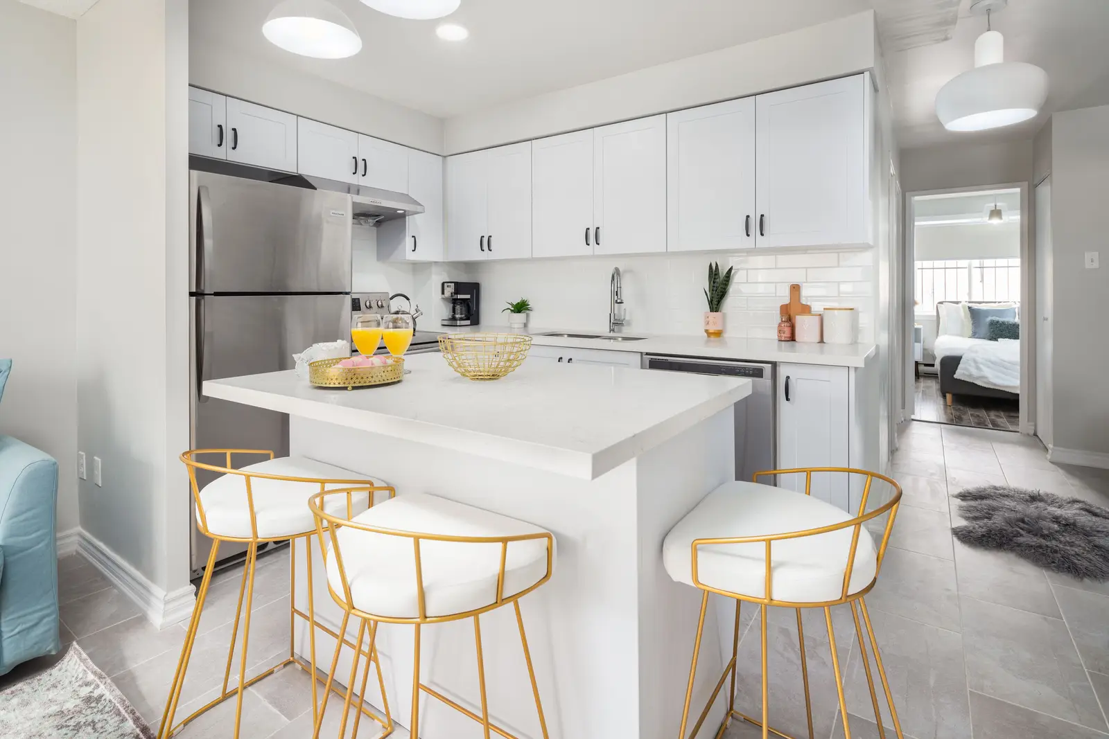 Interior of an apartment on Clinton Street in Toronto, with a blue sofa, a yellow chair, and a white kitchen.