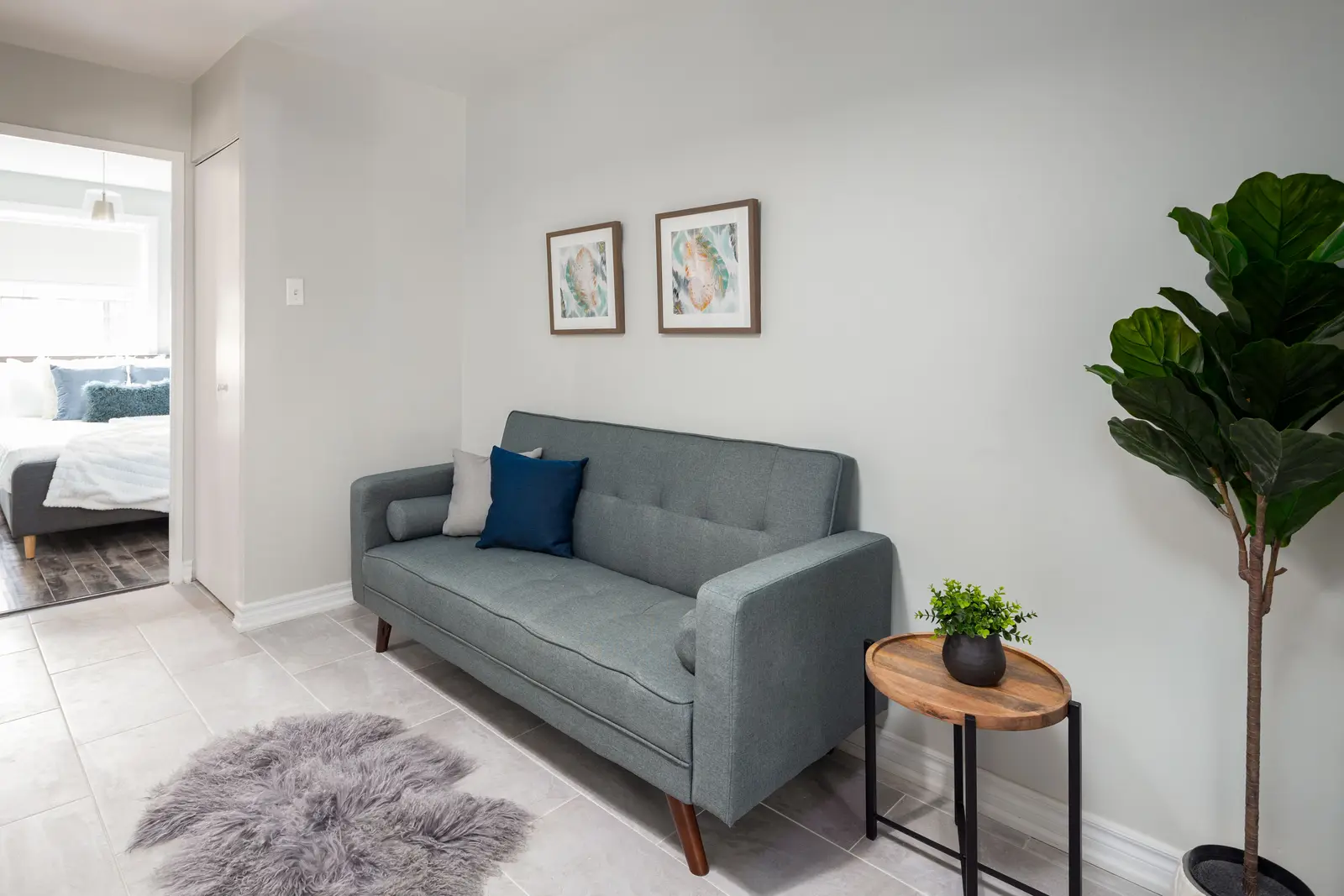 Interior of an apartment on Clinton Street in Toronto, with a blue sofa, a yellow chair, and a white kitchen.