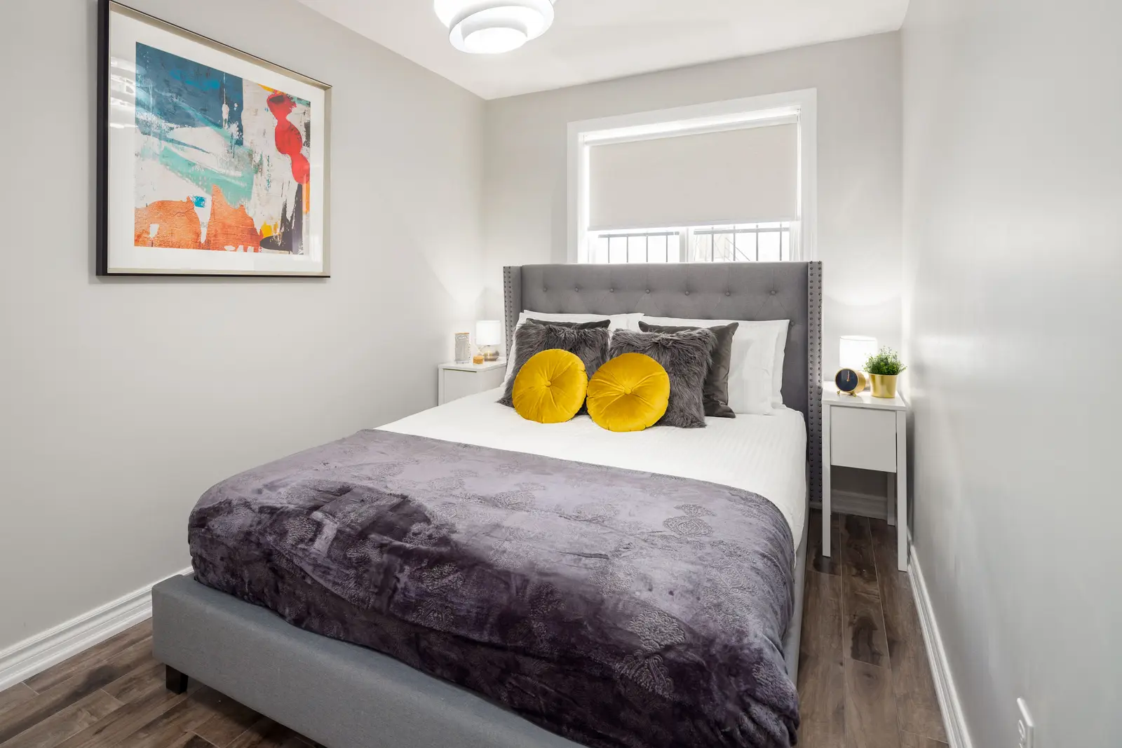 Interior of an apartment on Clinton Street in Toronto, with a blue sofa, a yellow chair, and a white kitchen.