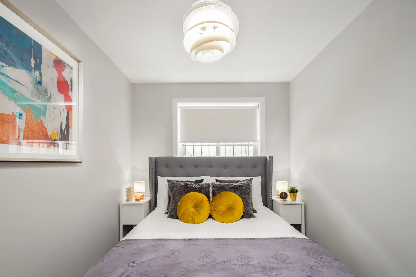 Interior of an apartment on Clinton Street in Toronto, with a blue sofa, a yellow chair, and a white kitchen.