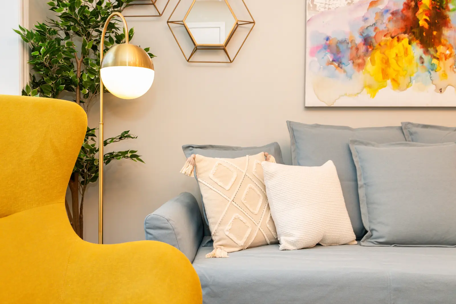 Interior of an apartment on Clinton Street in Toronto, with a blue sofa, a yellow chair, and a white kitchen.