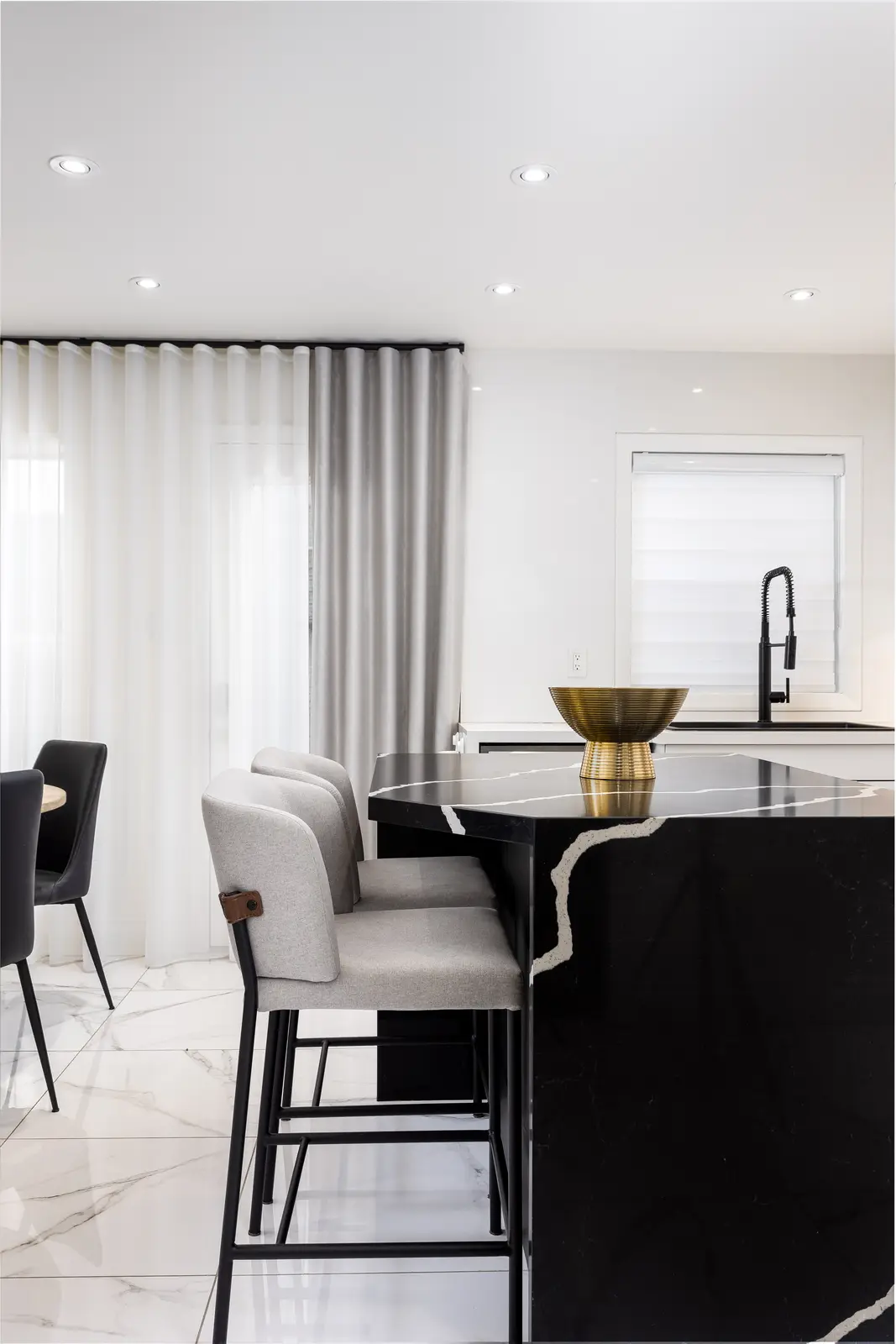 Interior of an Oakville house, with a dark dining table, light wood floors, and a white living room.