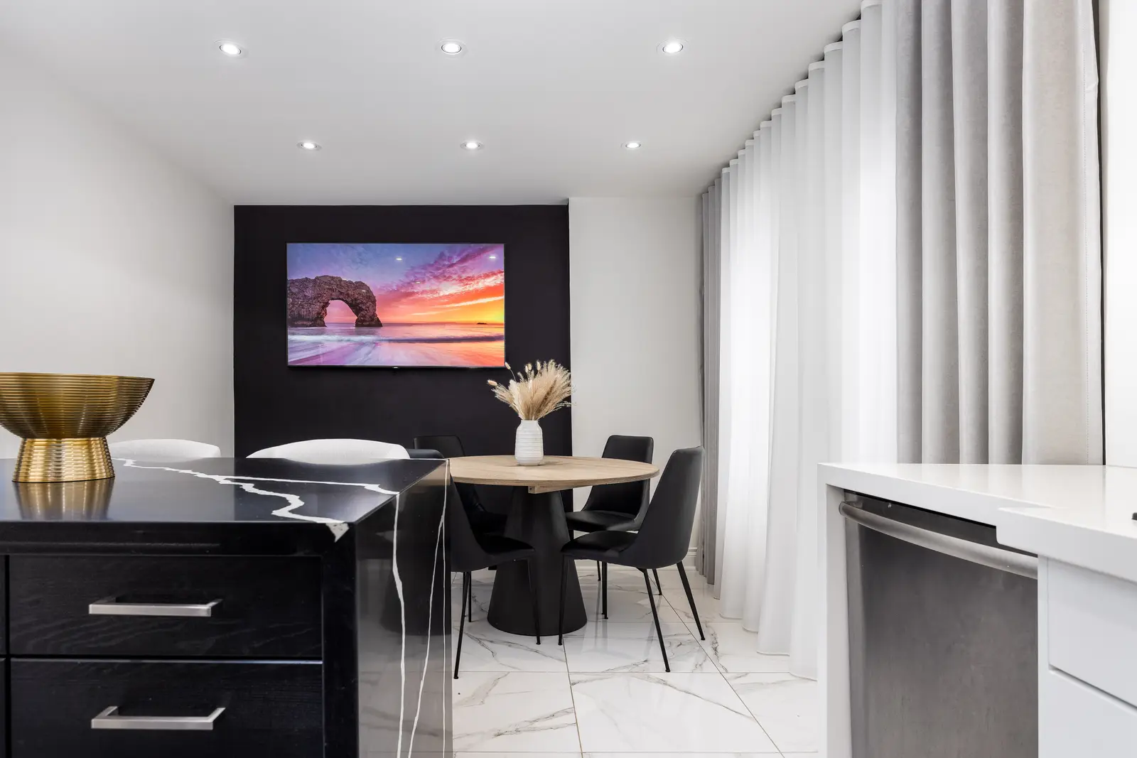 Interior of an Oakville house, with a dark dining table, light wood floors, and a white living room.