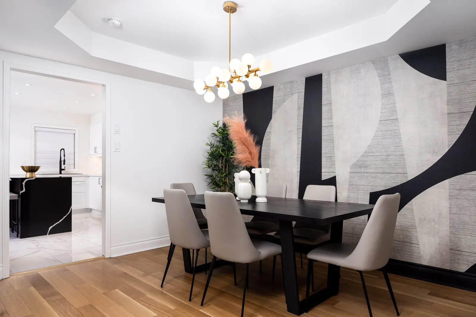 Interior of an Oakville house, with a dark dining table, light wood floors, and a white living room.