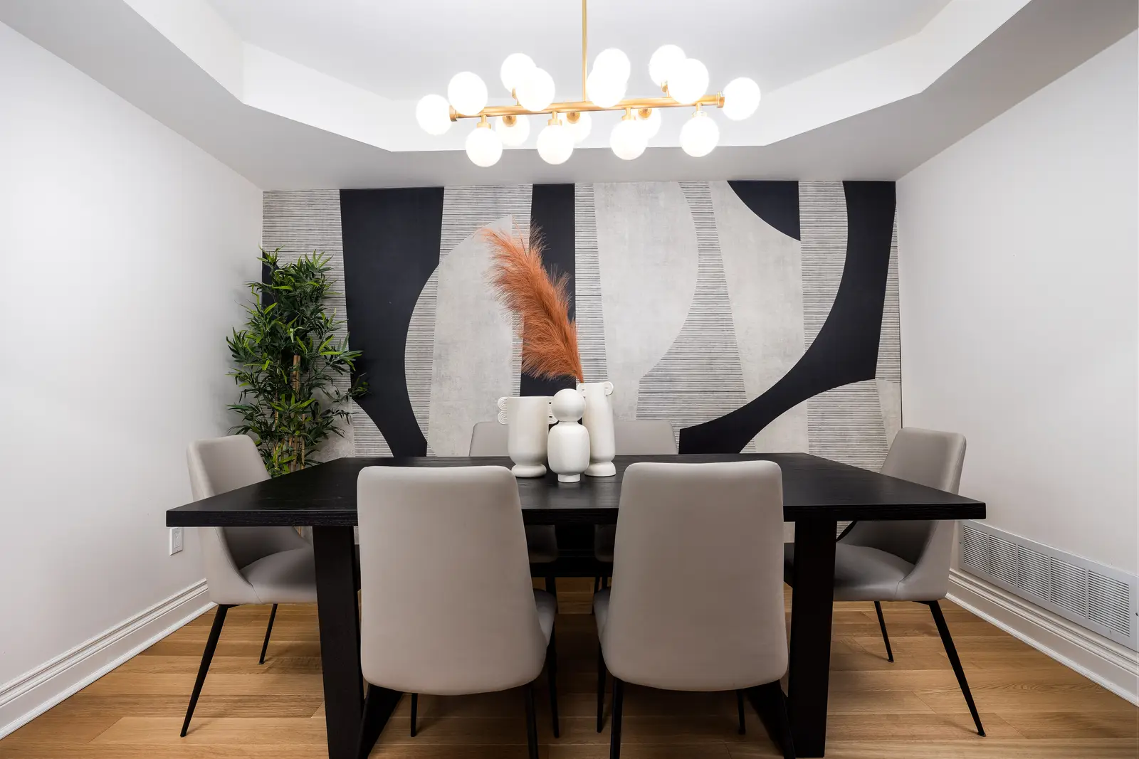 Interior of an Oakville house, with a dark dining table, light wood floors, and a white living room.