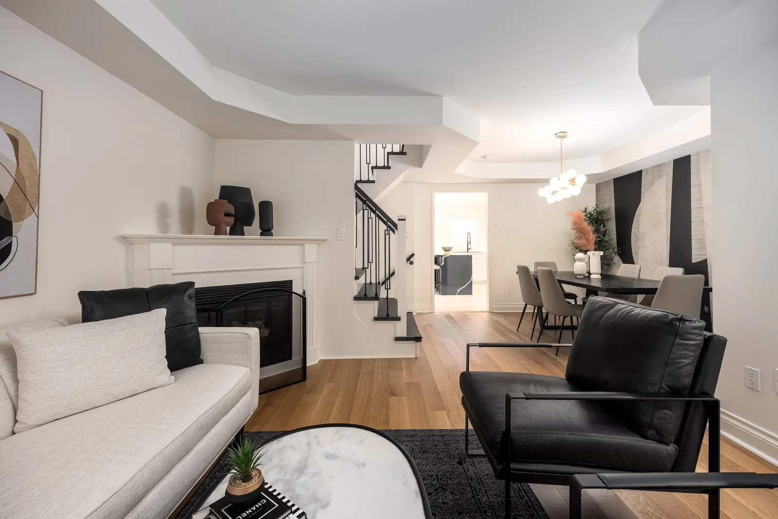 Interior of an Oakville house, with a dark dining table, light wood floors, and a white living room.