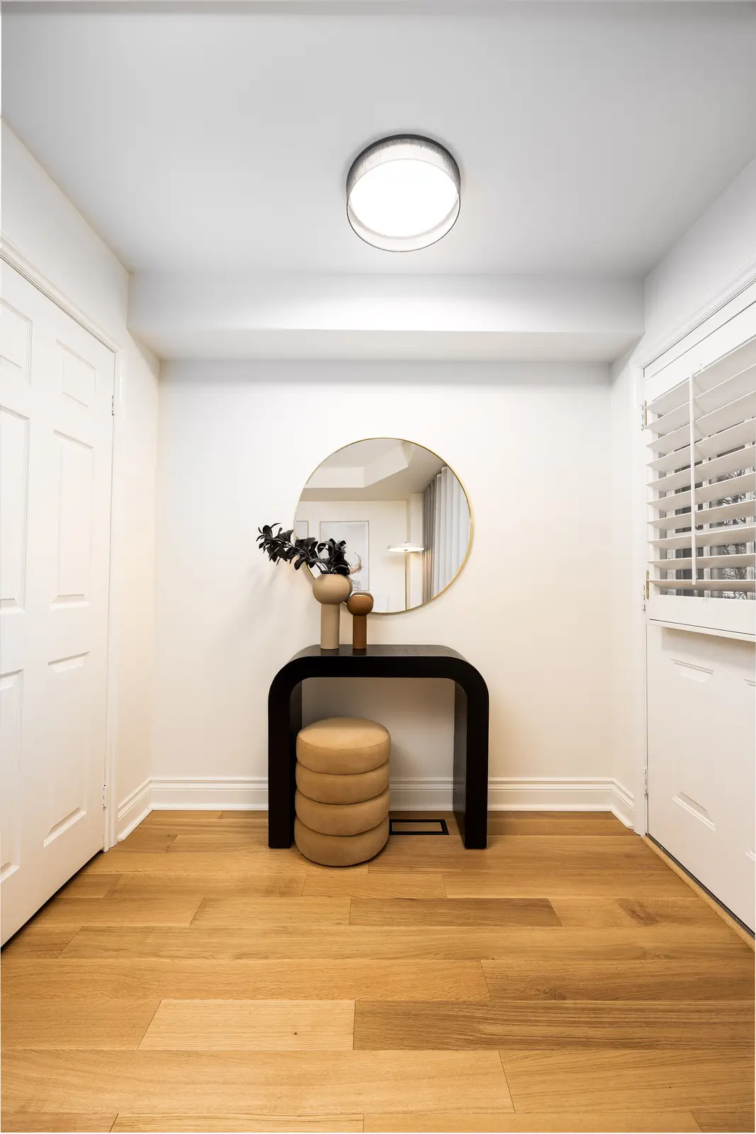 Interior of an Oakville house, with a dark dining table, light wood floors, and a white living room.