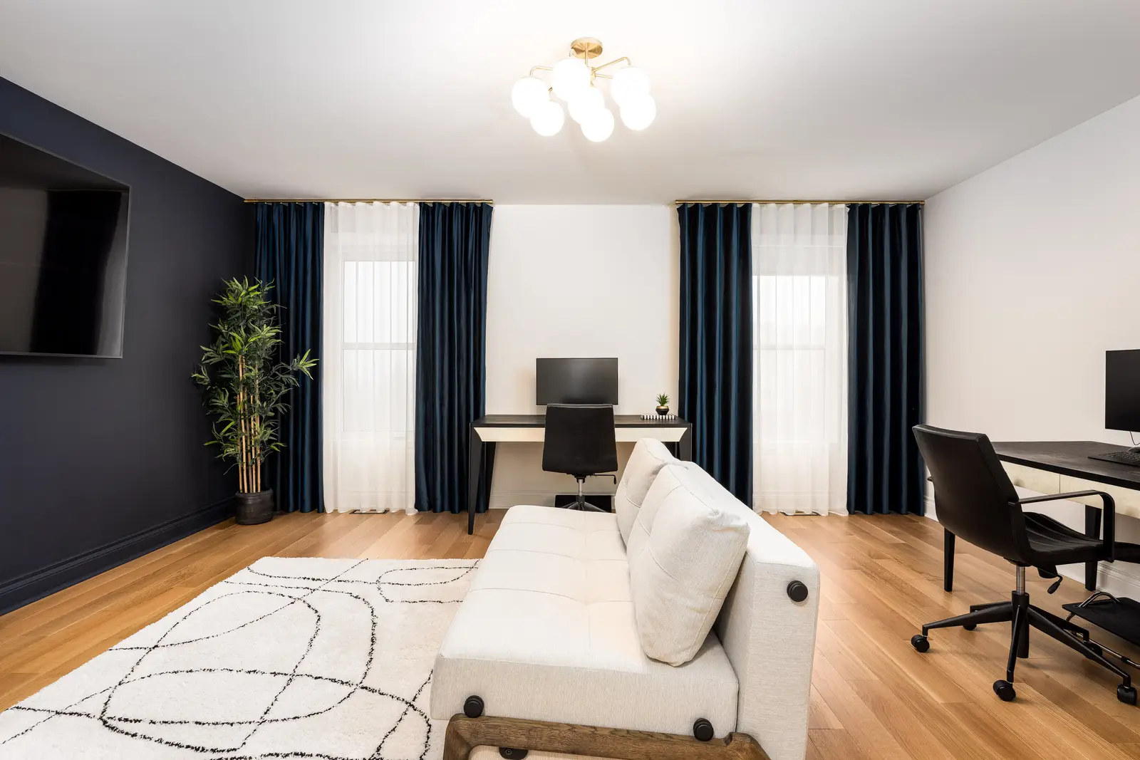 Interior of an Oakville house, with a dark dining table, light wood floors, and a white living room.